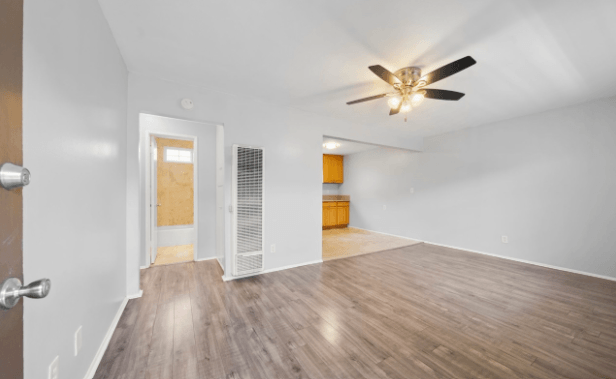 A room with a ceiling fan and wooden flooring.